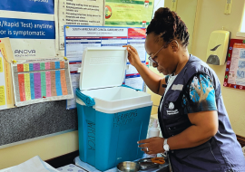 Dr. Simangele Mthethwa, Vaccine-Preventable Disease Surveillance Officer at WHO South Africa,  inspecting or preparing a vaccine cold box—a vital part of maintaining the cold chain required for storing and transporting vaccines at the correct temperature.
