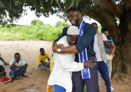 Mr. Supranational 2024, Dr. Fezile Mkhize, greets Pedro Mutaseque Paphelo, president of a leprosy selfcare group in Murrupula, Nampula, northern Mozambique, during a leprosy awareness campaign. Tiago Zenero/WHO Mozambique.